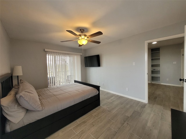 bedroom with hardwood / wood-style flooring, ceiling fan, and a spacious closet