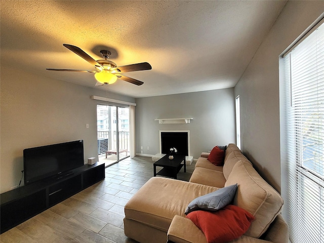 living room featuring ceiling fan, light hardwood / wood-style floors, and a textured ceiling