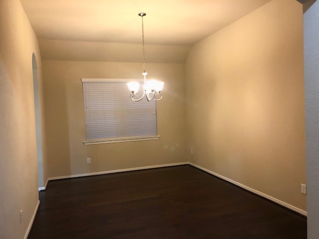 unfurnished room featuring dark hardwood / wood-style flooring, a chandelier, and vaulted ceiling