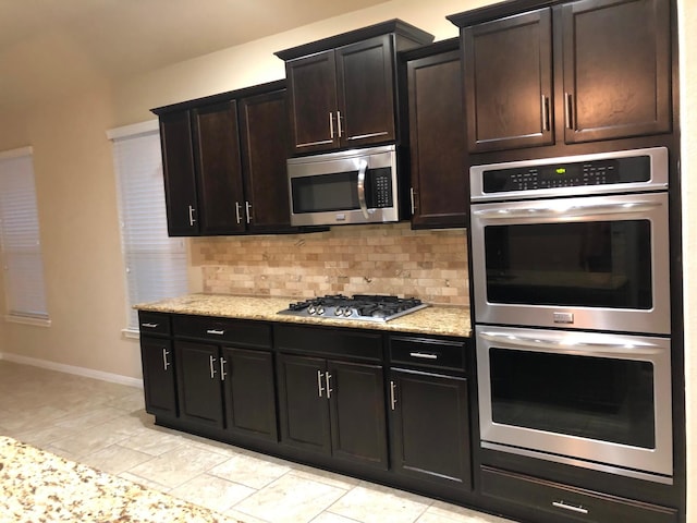 kitchen featuring light stone counters, backsplash, and stainless steel appliances