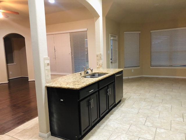 kitchen with sink, light stone counters, light tile patterned floors, dishwasher, and ceiling fan