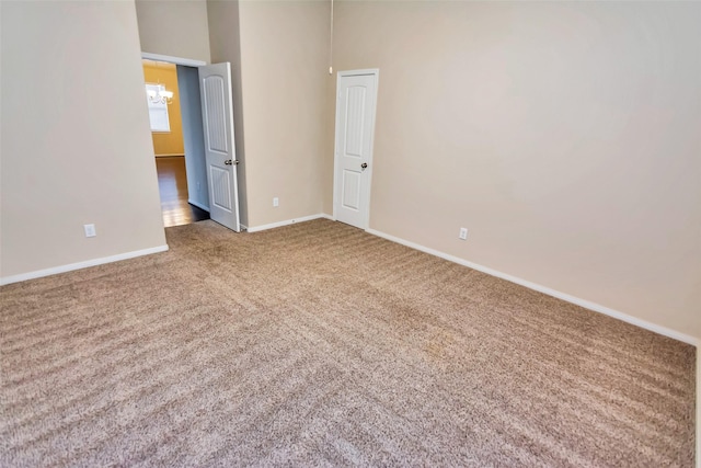 carpeted spare room with an inviting chandelier