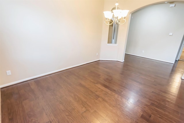 unfurnished room featuring a notable chandelier and dark hardwood / wood-style floors