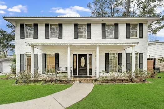 colonial-style house featuring a porch and a front yard