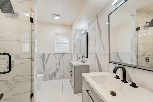 bathroom featuring walk in shower, vanity, and tile walls