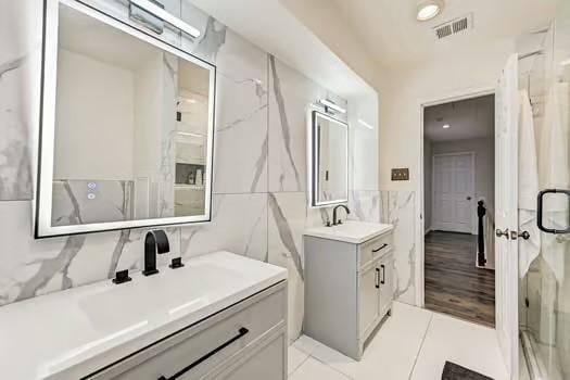 bathroom featuring vanity, tile walls, and a shower