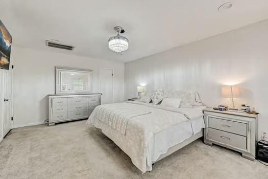 bedroom featuring light carpet and a notable chandelier