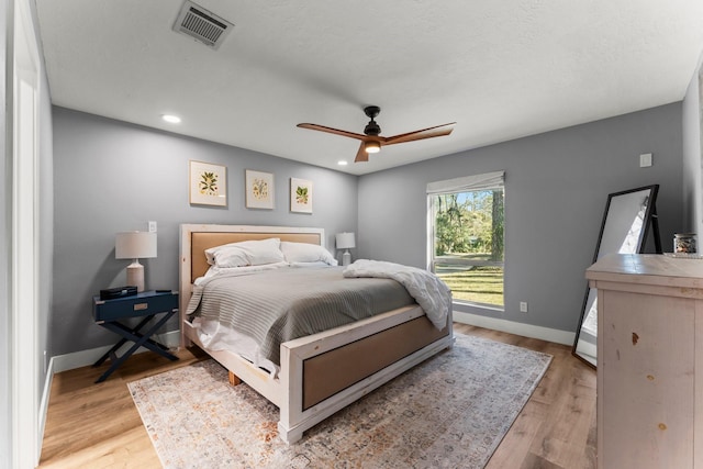 bedroom featuring ceiling fan, light hardwood / wood-style flooring, and a textured ceiling