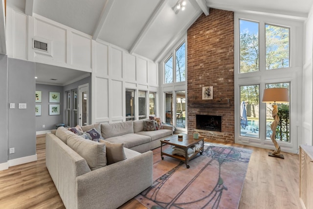 living room with light hardwood / wood-style flooring, a fireplace, high vaulted ceiling, and beamed ceiling