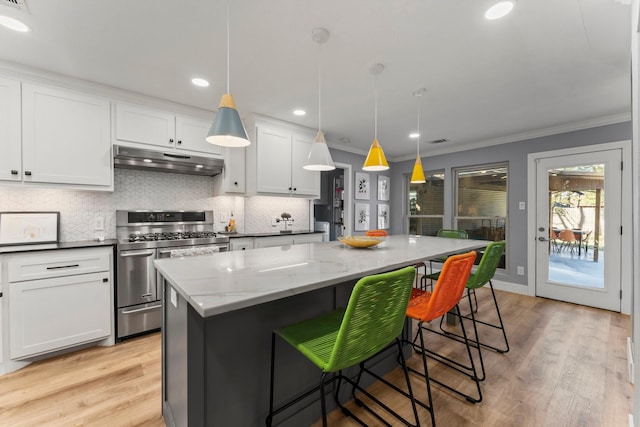 kitchen with dark stone countertops, double oven range, a center island, white cabinets, and decorative light fixtures