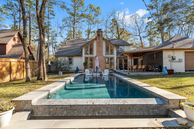 back of property with a fenced in pool, a patio, and a lawn