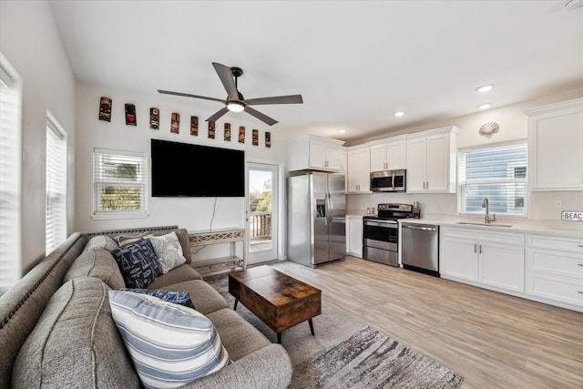 living room featuring sink, ceiling fan, and light hardwood / wood-style flooring