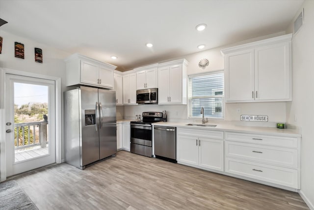 kitchen with white cabinetry, sink, stainless steel appliances, and light hardwood / wood-style floors