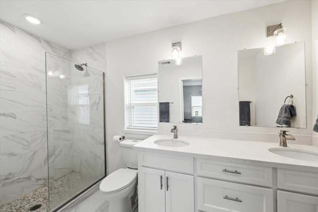 bathroom featuring a tile shower, vanity, and toilet