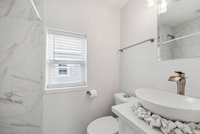 bathroom with toilet, sink, and a tile shower