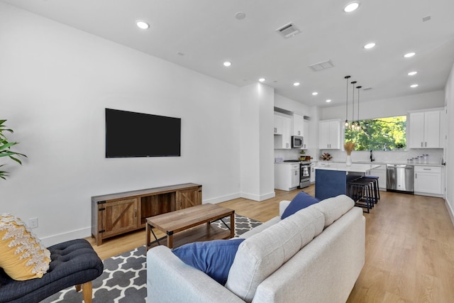 living room featuring recessed lighting, visible vents, and light wood-style flooring