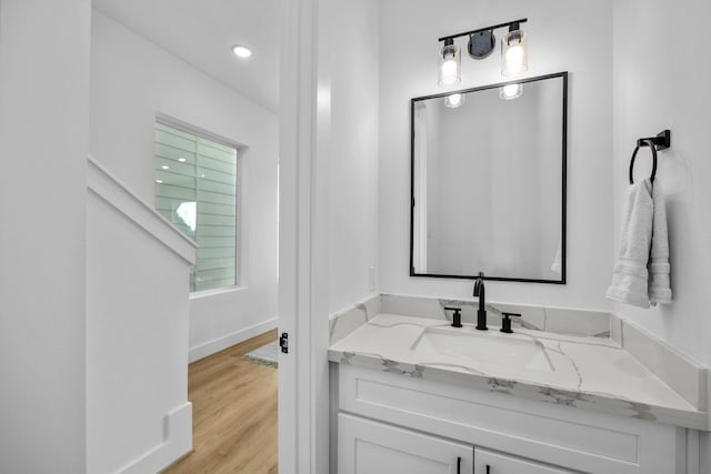 bathroom with vanity, wood finished floors, and baseboards