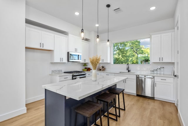 kitchen with a sink, decorative backsplash, appliances with stainless steel finishes, and white cabinets