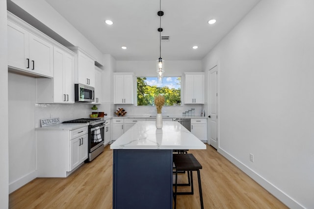 kitchen featuring light wood finished floors, white cabinetry, a kitchen breakfast bar, and stainless steel appliances