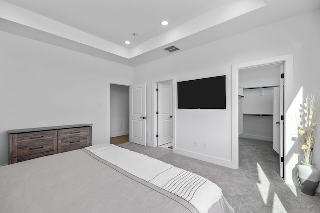 carpeted bedroom with visible vents, recessed lighting, baseboards, a raised ceiling, and a spacious closet