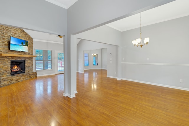 unfurnished living room featuring a stone fireplace, ceiling fan with notable chandelier, a high ceiling, crown molding, and light hardwood / wood-style flooring