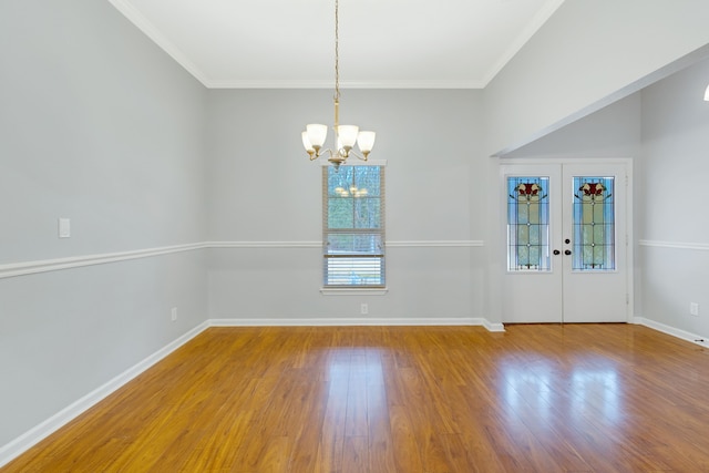 empty room with an inviting chandelier, crown molding, wood-type flooring, and french doors