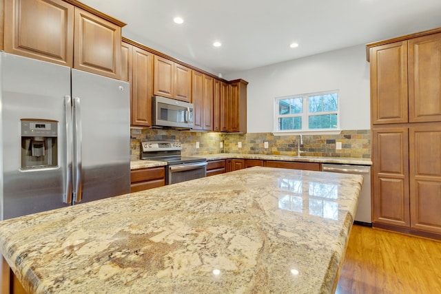 kitchen featuring light stone countertops, backsplash, stainless steel appliances, and sink