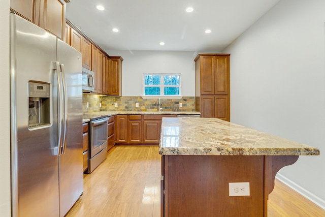 kitchen featuring tasteful backsplash, stainless steel appliances, a center island, and light hardwood / wood-style flooring