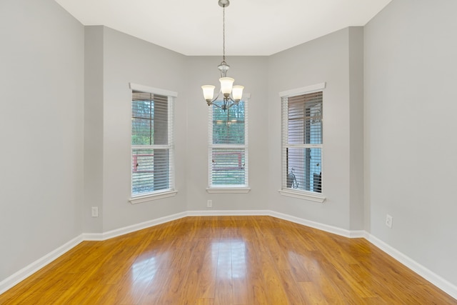 unfurnished room featuring a notable chandelier and hardwood / wood-style flooring