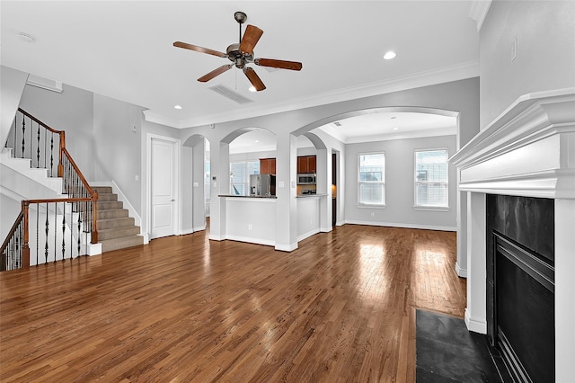 unfurnished living room with dark wood-type flooring, ornamental molding, and ceiling fan