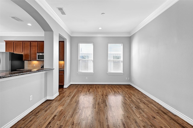 kitchen featuring dark hardwood / wood-style flooring, crown molding, fridge, and decorative backsplash