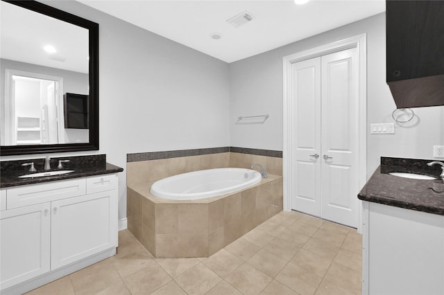 bathroom featuring vanity, tile patterned flooring, and tiled tub