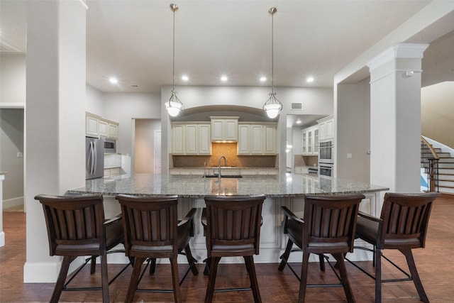 kitchen featuring stone counters, hanging light fixtures, stainless steel appliances, dark hardwood / wood-style floors, and tasteful backsplash