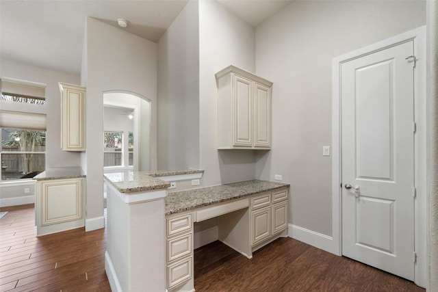 kitchen featuring a peninsula, light stone countertops, built in desk, and cream cabinetry