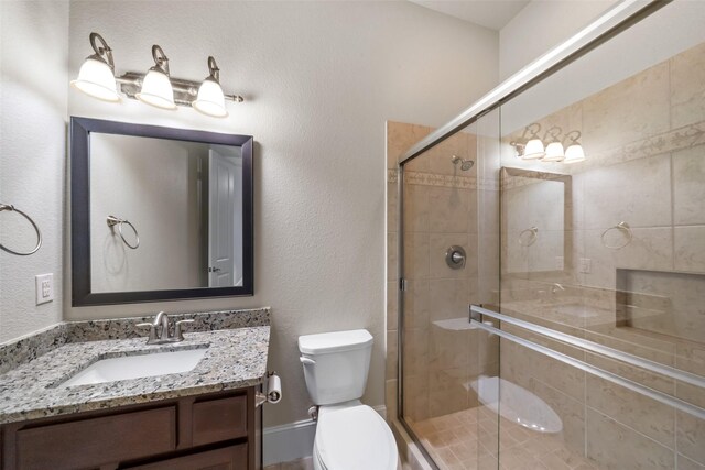 bathroom with vanity, a shower with door, and toilet