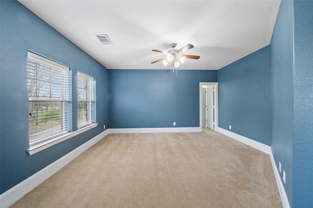 unfurnished room featuring a ceiling fan, visible vents, light carpet, and baseboards