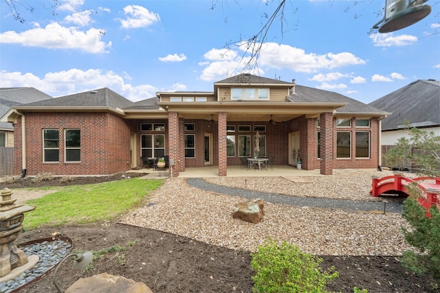 rear view of house featuring brick siding, fence, and a patio