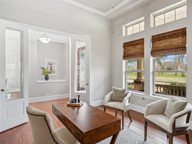 living area with crown molding, baseboards, and wood finished floors