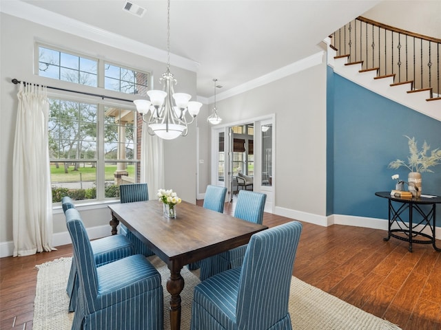 dining space with dark wood-style flooring, crown molding, visible vents, an inviting chandelier, and baseboards