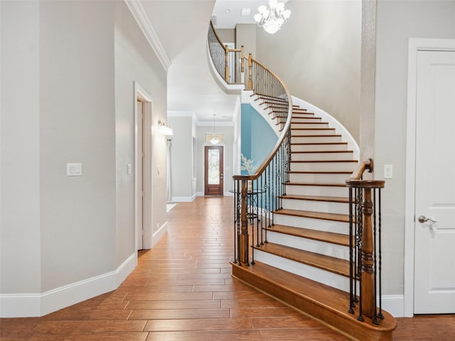 entryway featuring baseboards, wood finished floors, stairs, and crown molding