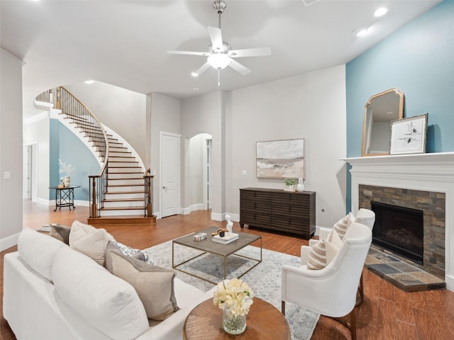 living room featuring arched walkways, a fireplace, and wood finished floors