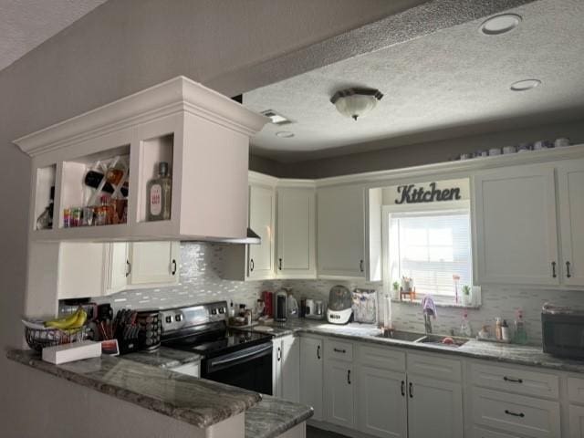 kitchen featuring light stone countertops, stainless steel range with electric cooktop, kitchen peninsula, and white cabinets