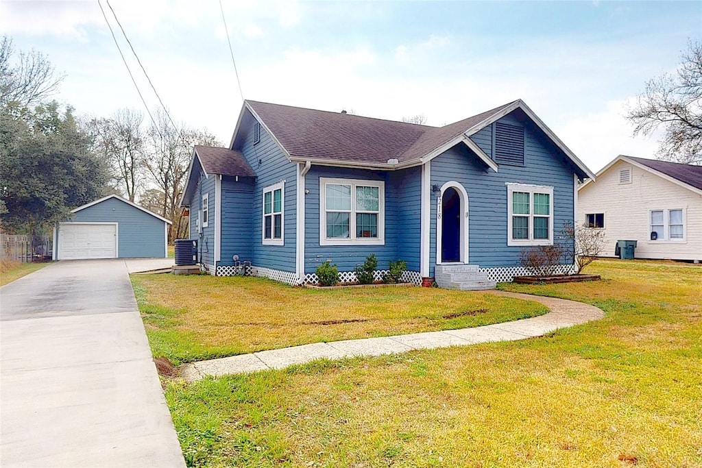 view of front of home featuring cooling unit, a garage, an outdoor structure, and a front lawn