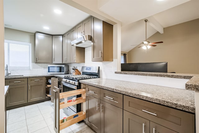 kitchen with light stone counters, sink, decorative backsplash, and appliances with stainless steel finishes