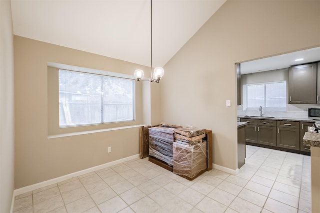 kitchen with vaulted ceiling, light tile patterned flooring, decorative light fixtures, sink, and an inviting chandelier