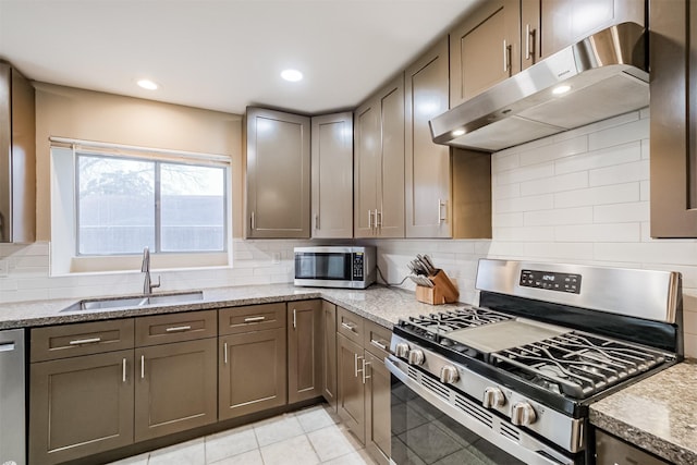 kitchen with sink, light tile patterned floors, backsplash, stainless steel appliances, and light stone countertops