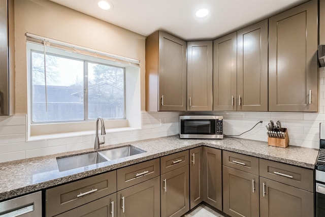 kitchen with tasteful backsplash, sink, stainless steel appliances, and light stone countertops