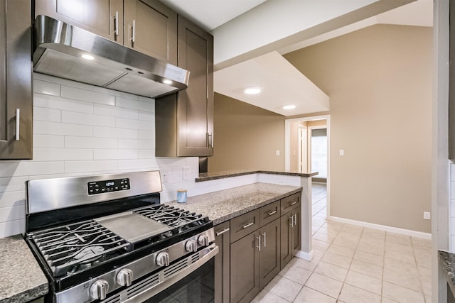 kitchen with light tile patterned flooring, dark brown cabinetry, gas range, light stone counters, and backsplash