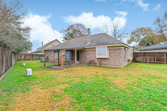 back of property featuring central air condition unit and a lawn