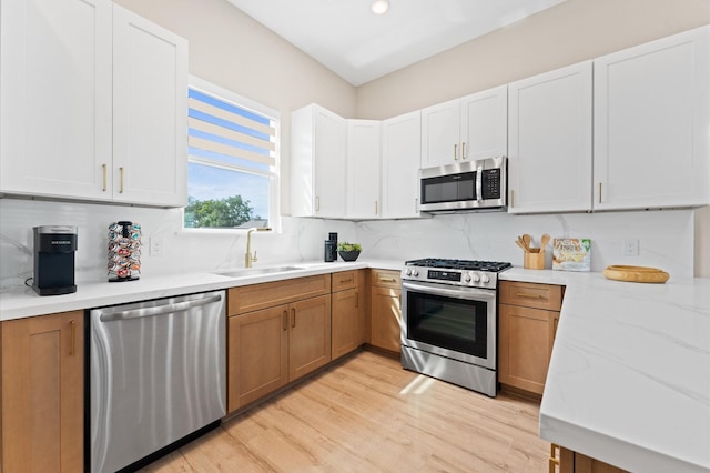 kitchen featuring tasteful backsplash, stainless steel appliances, light wood finished floors, and a sink